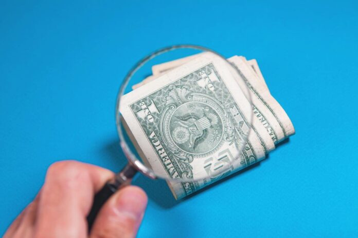 Magnifying glass over folded us dollar bills
