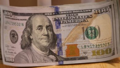 a stack of one hundred dollar bills sitting on top of a wooden table